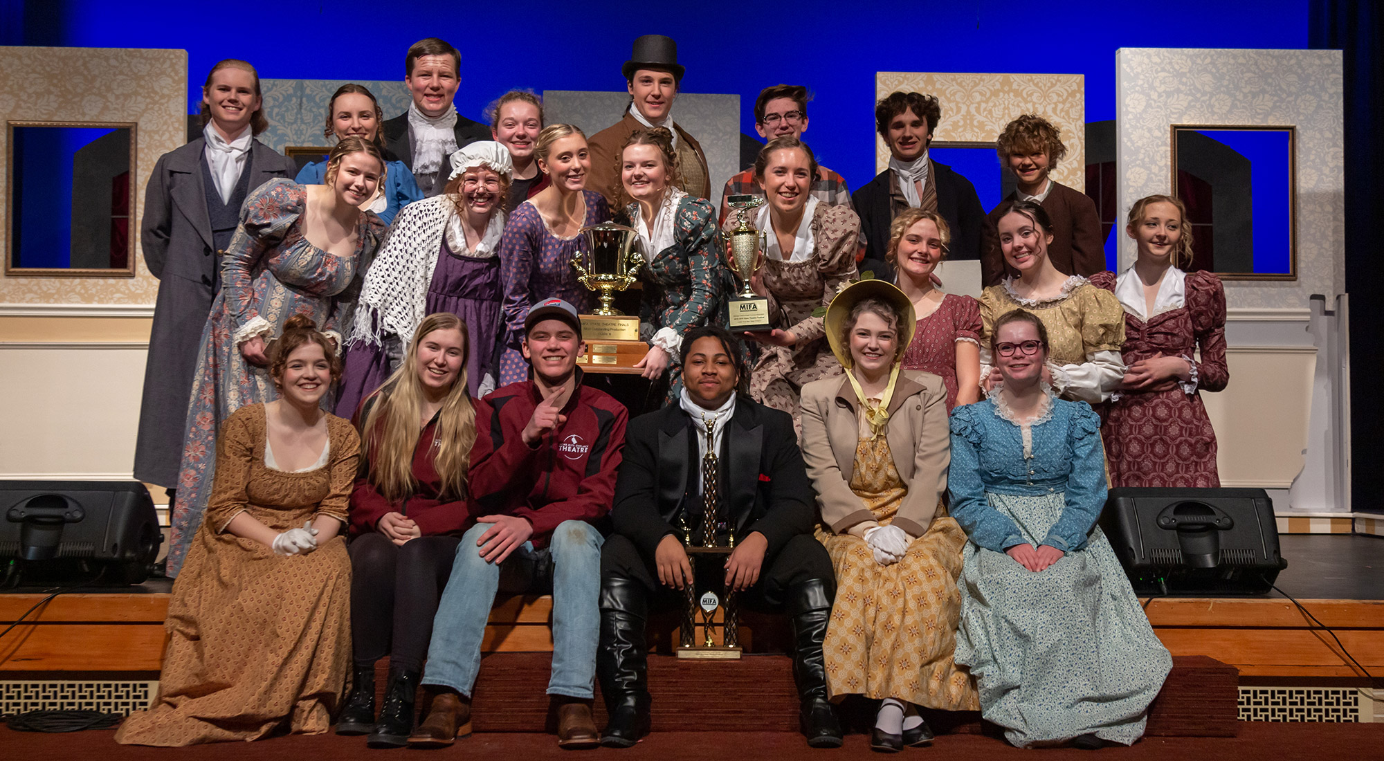 The 2022 state winning MIFA team posing in costume with their trophy and smiling at the camera