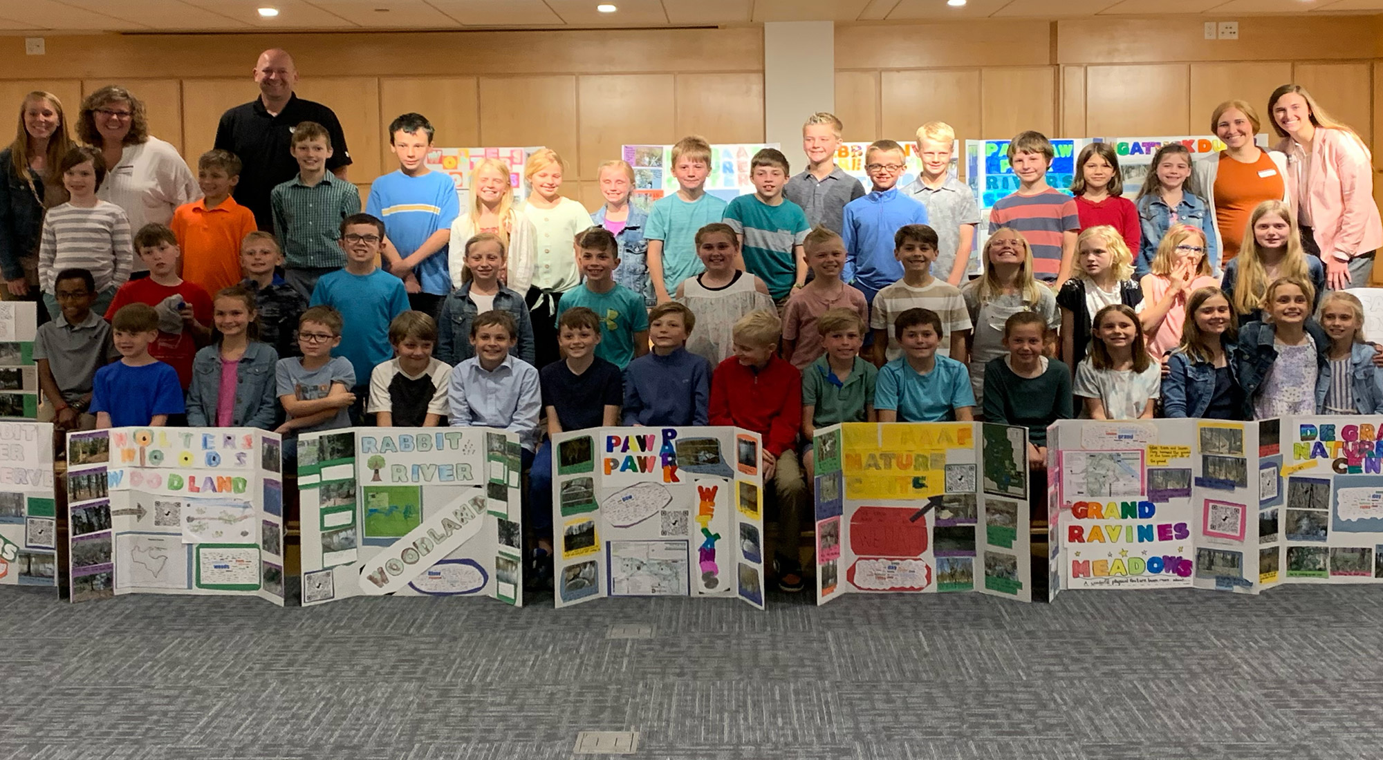 3rd graders holding posters looking at camera