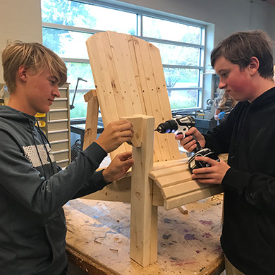 2 boys drilling an Adirondack chair