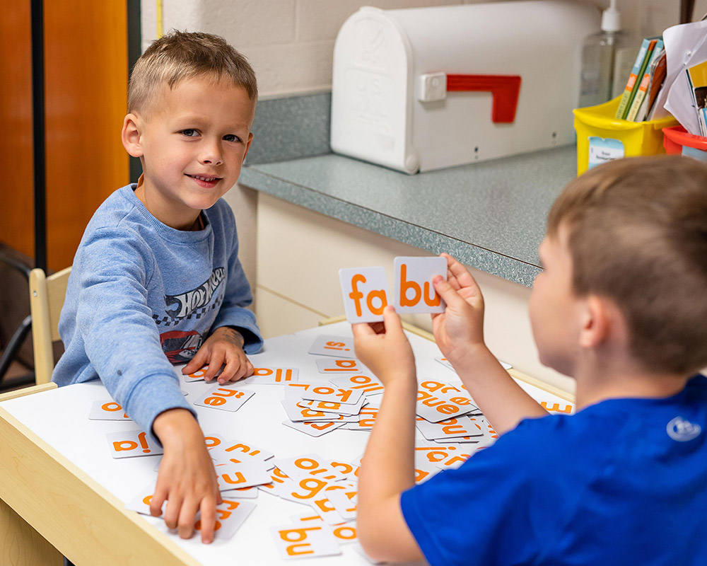 2 male kindergartners putting word cards together