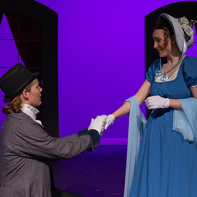 Actor kneeling, holding actress's hand