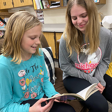 HCHS SPanish Immersion intern student reading with a 3rd grade ZCS Spanish Immersion female student