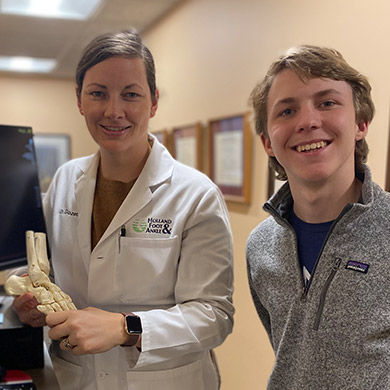 HCHS Spanish Immersion intern smiling at the camera with the podiatrist holding a foot skeleton.