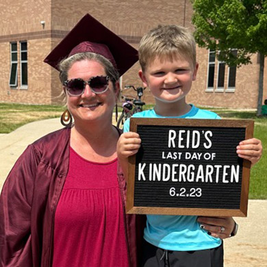 Mrs. Brouwer dressed in a graduation outfit with a kindergarten student on the last day of kindergarten