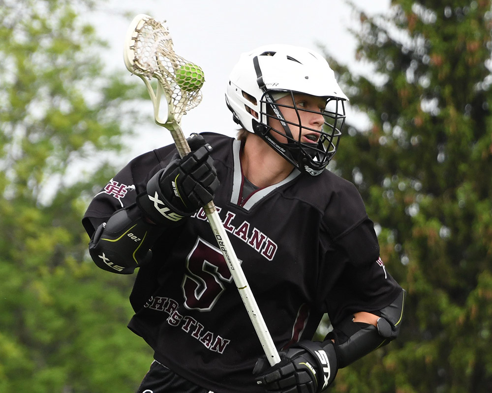 Middle school boy lacrosse player running with the ball