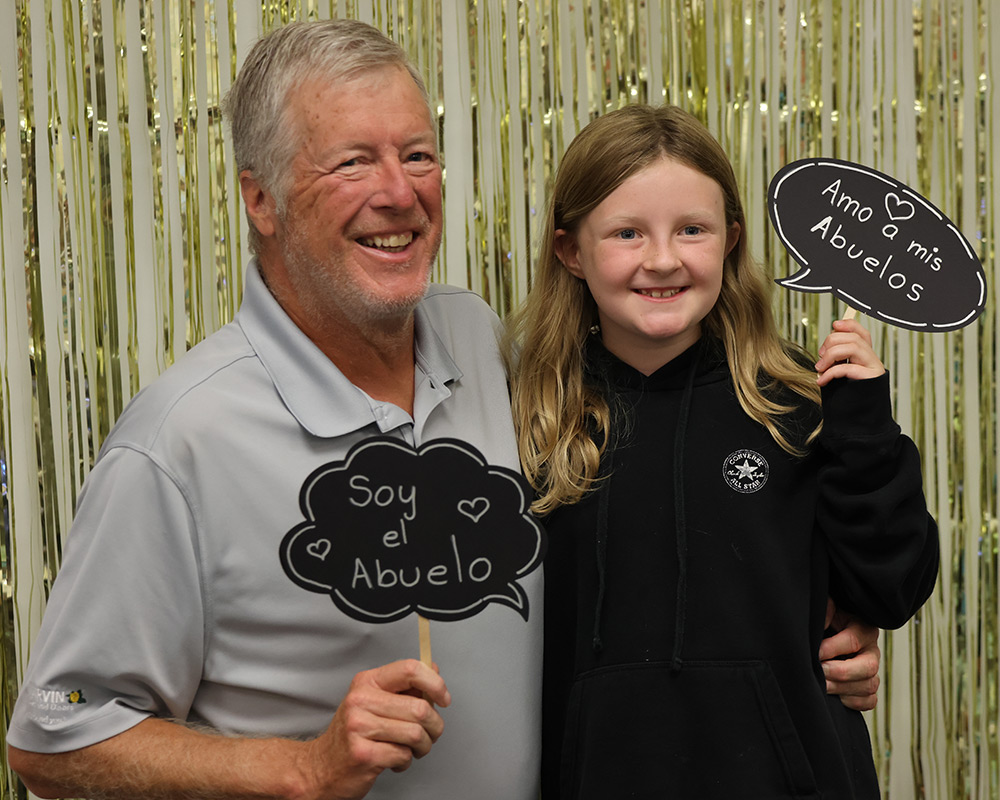 Grandpa and grandaughter holding abuelo signs and smiling at the camera