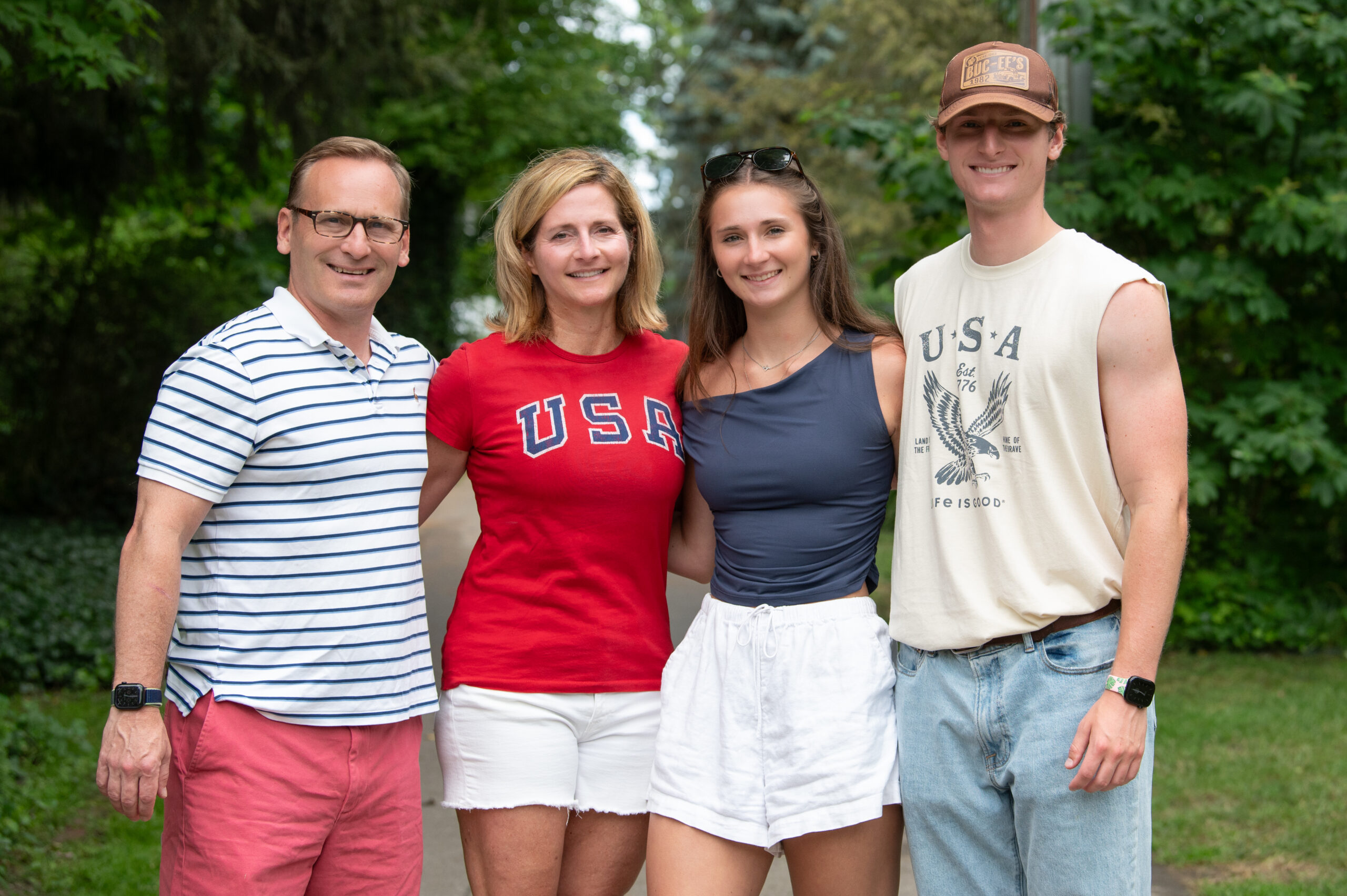 Four members of the Armstrong family smiling at the camera, standing outside