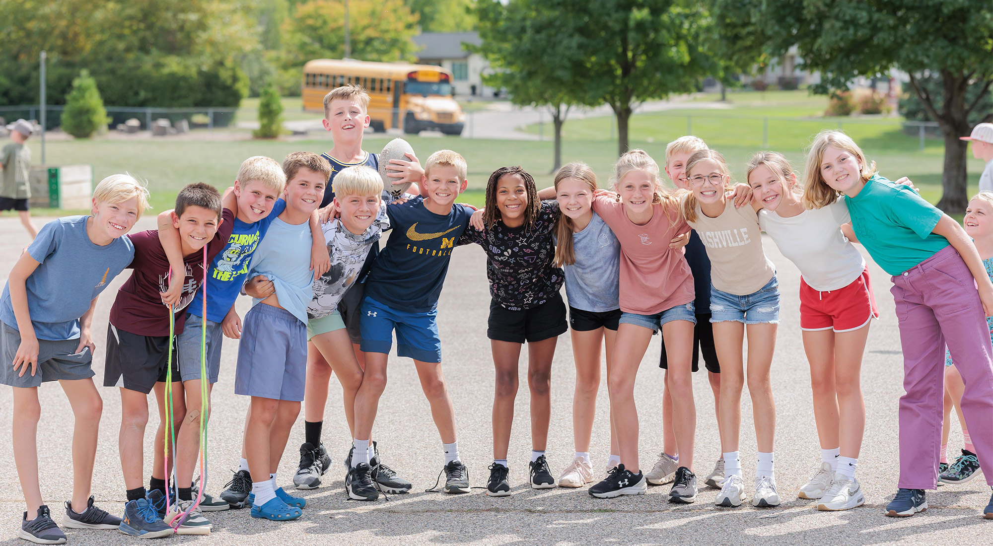 Pine Ridge students standing together and smiling at the camera, dressed in shorts on the playground