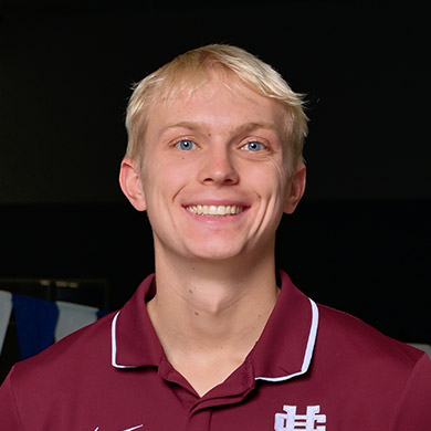 Boys swimming coach Blake Assink smiling at the camera.