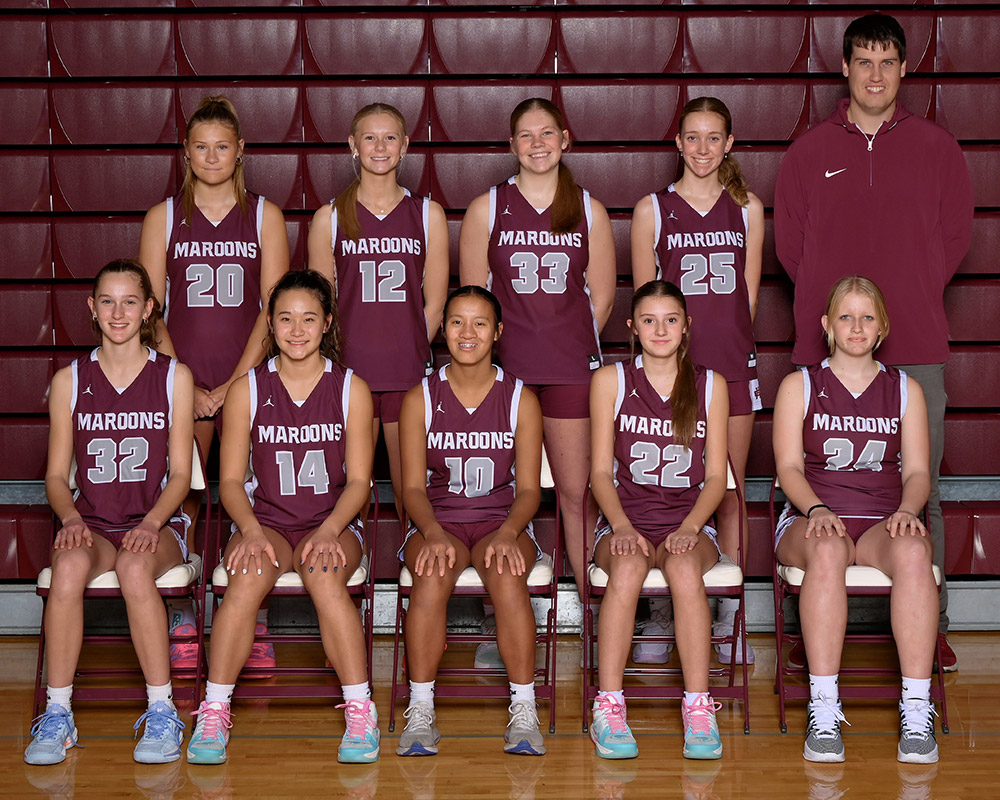 Freshmen girls basketball team dressed in maroon uniforms smiling at the camera