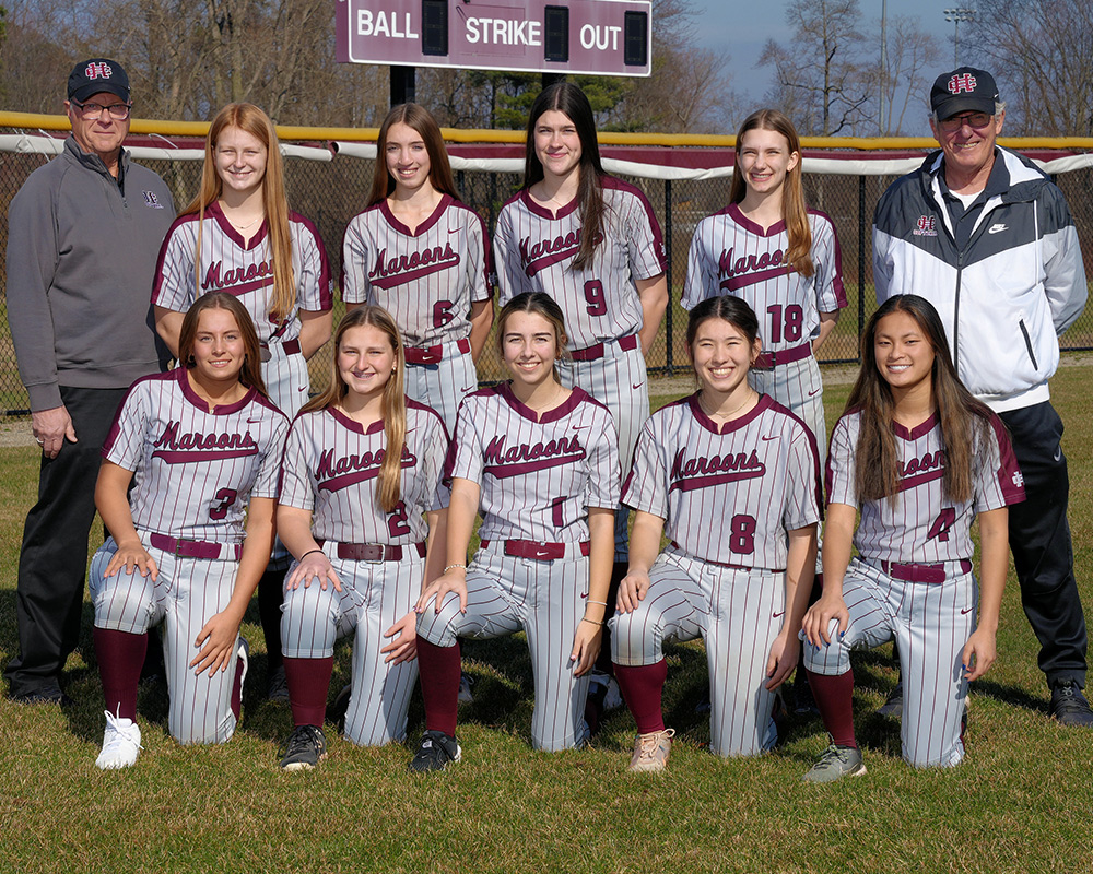 JV girls softball team wearing striped uniforms, outside, smiling at the camera