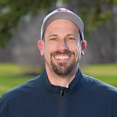 Boys varsity golf coach standing outside, smiling at the camera